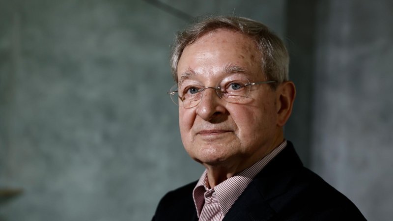 Der ungarische Schriftsteller und Fotograf Péter Nádas blickt vor grauem Hintergrund in der Akademie der Künste in die Kamera. 