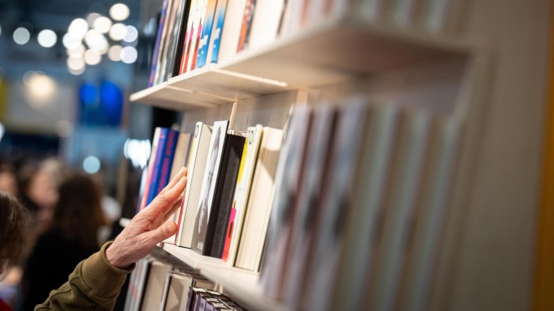 Hand geht durch ein Bücherreagl
