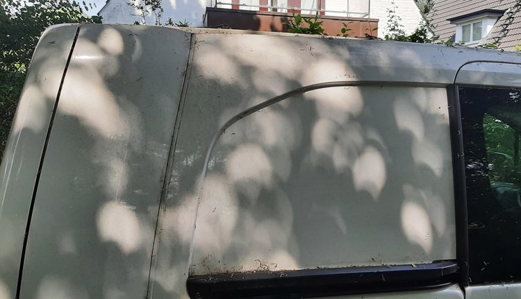Auf einem weißen Auto sind viele Bilder der Sonne zu sehen. Sie erscheinen kreisrund, sind aber durch den Mond jeweils etwas angebissen.