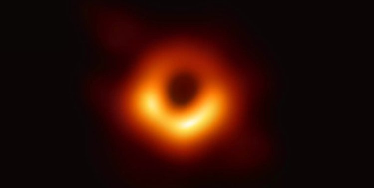 Vor schwarzem Hintergrund steht ein orange-rötlicher Ring mit einigen helleren Verdickungen, der einen dunklen Bereich umgibt.